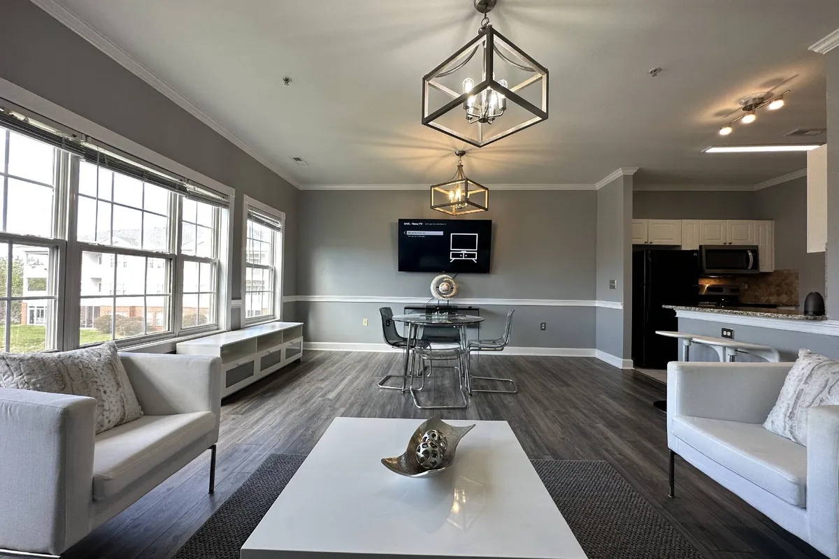 This welcoming living and dining area features a comfortable sofa, a stylish dining table set for sharing meals, bright contemporary lighting fixtures, and a television. The open layout encourages social gatherings and family interactions, making it an ideal setting for relaxing evenings or special celebrations.