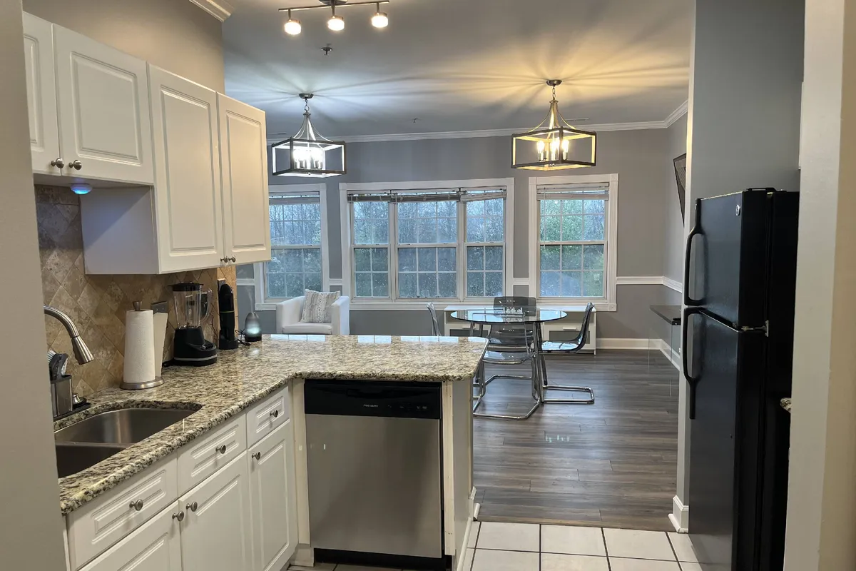 A contemporary dining area with a table and chairs situated near large windows, seamlessly connected to the kitchen. The atmosphere is inviting and versatile, ready for intimate dinners, family meals, or festive celebrations.