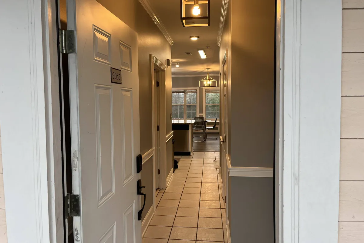 This image captures the entryway and kitchen area of the condo, with warm lighting, a welcoming front door, and inviting spaces that suggest ease of movement and comfort. The kitchen’s proximity to the entrance and the visible windows imply an open, flexible layout, ideal for both socializing and everyday living.