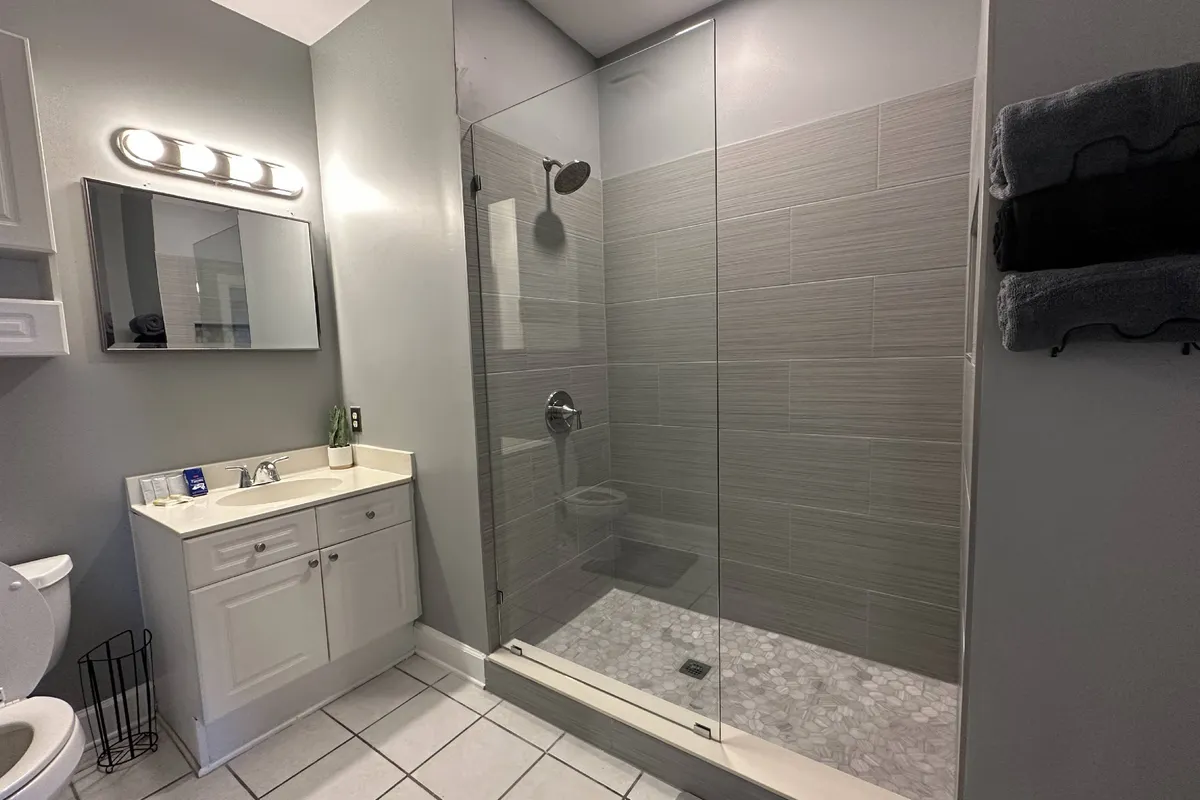 A calm and refreshing bathroom interior with a glass shower enclosure, vanity sink, mirror, and toilet. The soft lighting and tidy layout create a soothing ambiance, ideal for morning routines or unwinding in the evening.